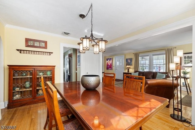 dining space featuring light wood-style flooring, visible vents, ornamental molding, and a chandelier