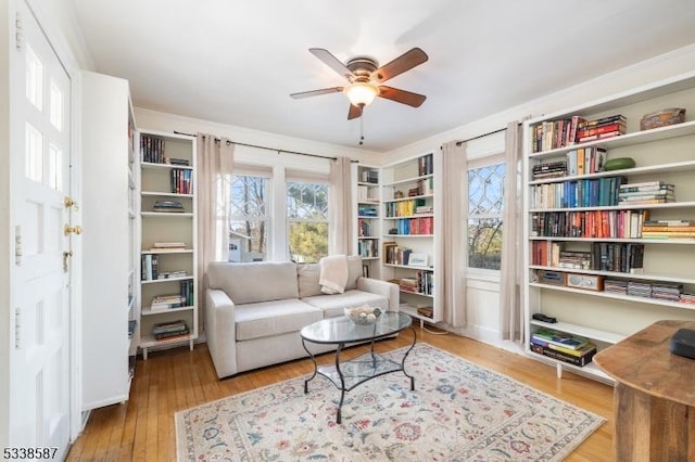 living area with light wood-style floors and a ceiling fan