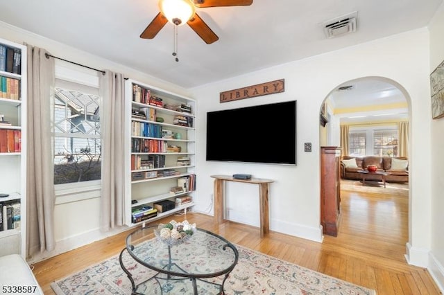 sitting room featuring arched walkways, ceiling fan, light wood-style flooring, visible vents, and baseboards