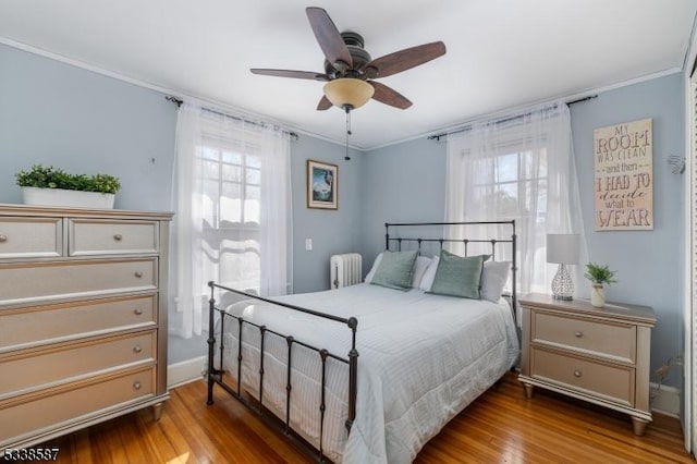 bedroom featuring radiator heating unit, ornamental molding, and wood finished floors