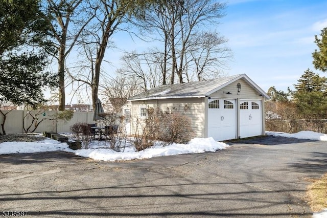 snow covered garage with a detached garage and fence