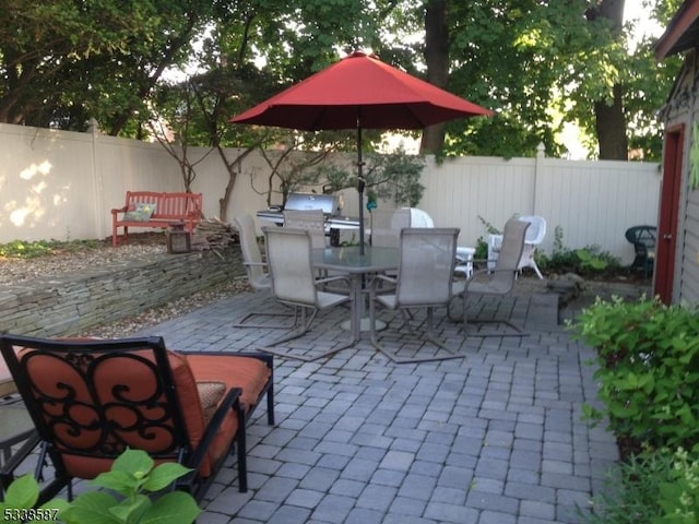 view of patio with outdoor dining area, fence private yard, and a grill