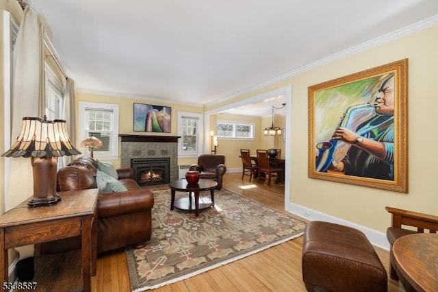 living room featuring crown molding, baseboards, wood finished floors, and a tile fireplace