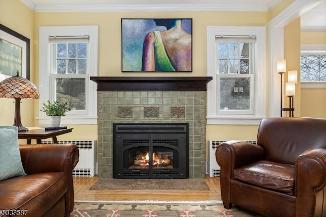 sitting room with a fireplace with flush hearth, plenty of natural light, ornamental molding, and radiator heating unit