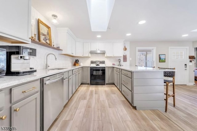 kitchen with electric stove, sink, a breakfast bar, dishwasher, and kitchen peninsula