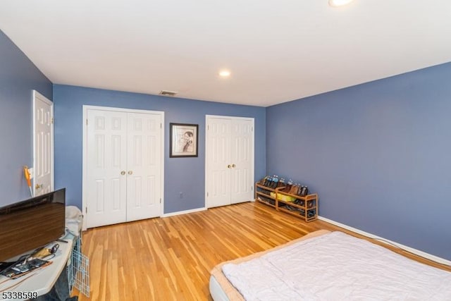 bedroom with hardwood / wood-style floors and multiple closets