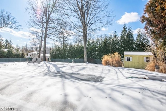 snowy yard featuring a shed