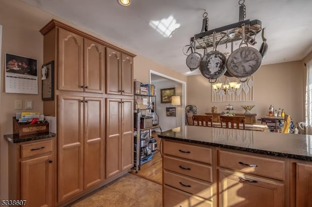 kitchen featuring an inviting chandelier and dark stone countertops