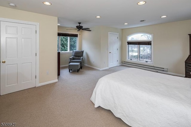 carpeted bedroom with ceiling fan, multiple windows, and a baseboard radiator