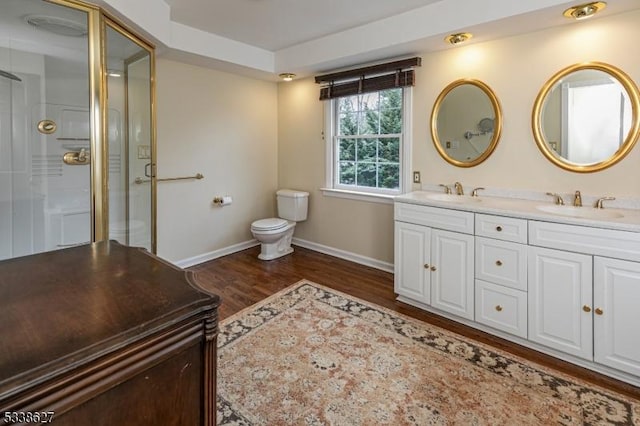 bathroom with toilet, vanity, an enclosed shower, and wood-type flooring