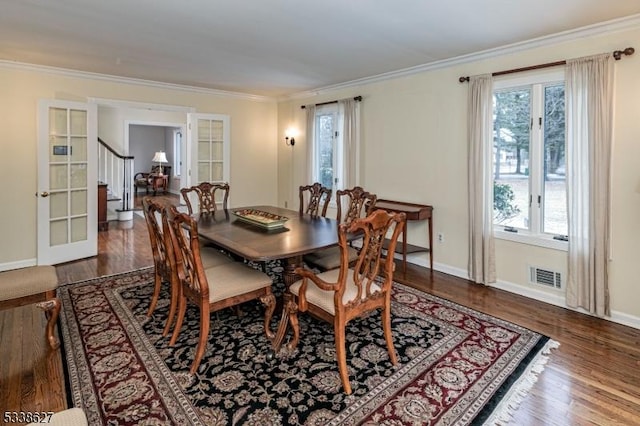 dining space with a wealth of natural light, crown molding, and dark hardwood / wood-style floors