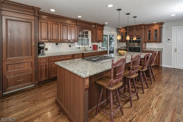 kitchen featuring appliances with stainless steel finishes, a kitchen island, pendant lighting, and dark hardwood / wood-style floors