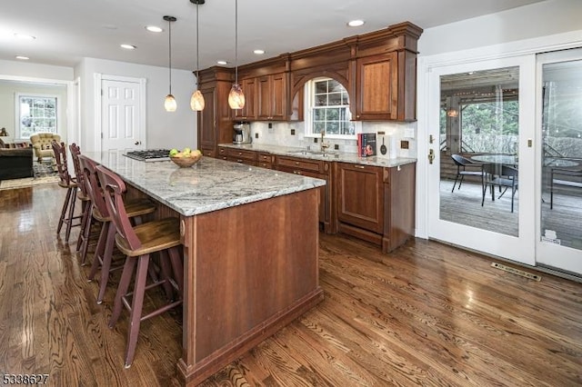 kitchen with a healthy amount of sunlight, a kitchen island, dark hardwood / wood-style floors, and decorative light fixtures