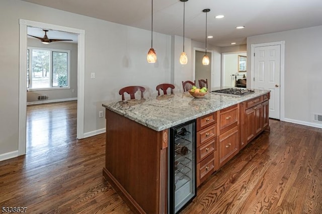 kitchen with dark wood-type flooring, wine cooler, decorative light fixtures, and a center island