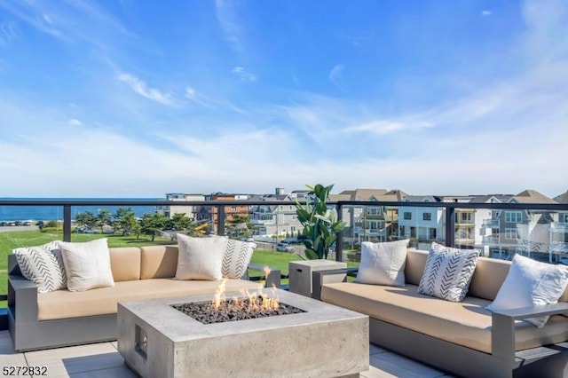 view of patio / terrace with a water view, a balcony, and an outdoor living space with a fire pit