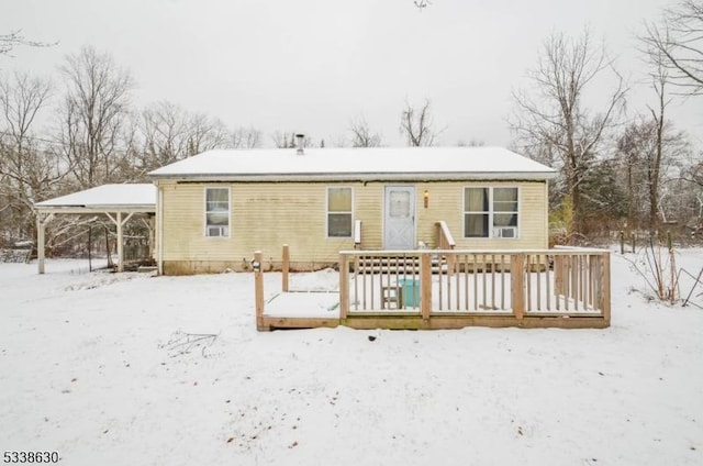 snow covered rear of property with a deck