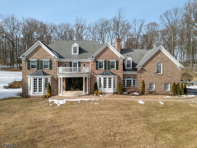 back of house featuring a yard, french doors, a chimney, and brick siding