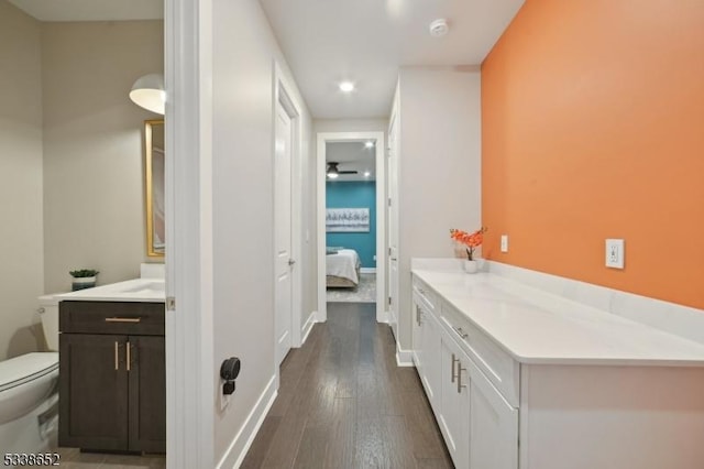 bathroom featuring toilet, connected bathroom, vanity, wood finished floors, and baseboards