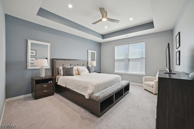 bedroom with a tray ceiling, light carpet, baseboards, and recessed lighting