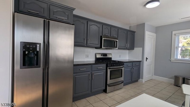 kitchen with light tile patterned floors, stainless steel appliances, visible vents, baseboards, and tasteful backsplash