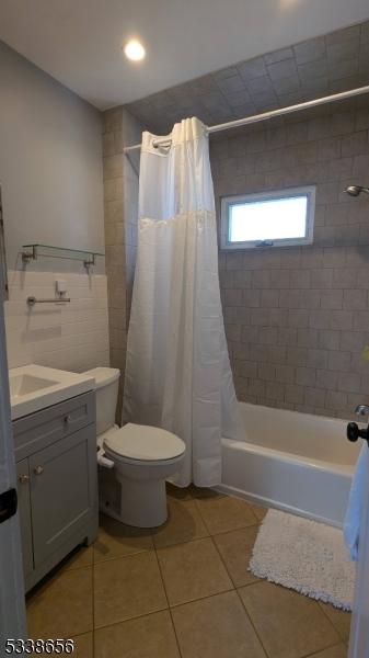 bathroom featuring toilet, tile patterned flooring, shower / bath combination with curtain, and vanity