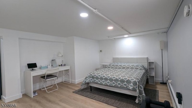 bedroom featuring a baseboard radiator, baseboards, wood finished floors, and recessed lighting