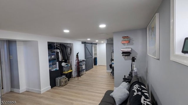 exercise area with light wood-type flooring, a barn door, baseboards, and recessed lighting