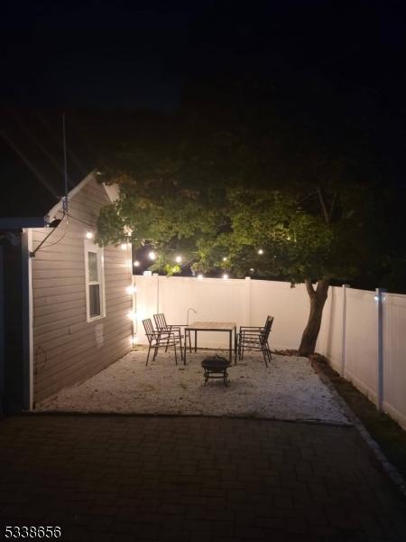 patio at night with an outdoor fire pit and a fenced backyard