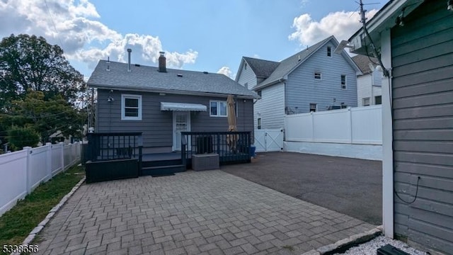 back of house with a patio area, a fenced backyard, a chimney, and a deck