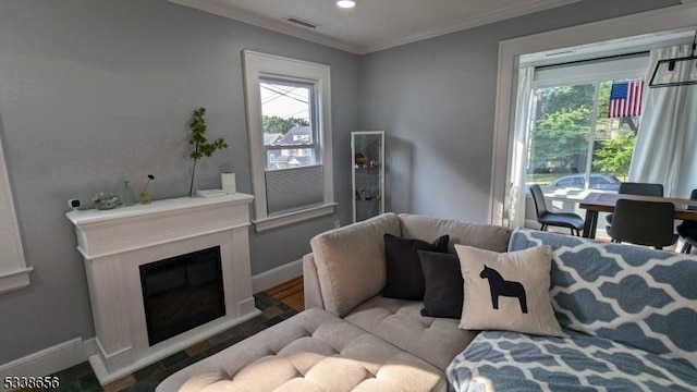 living area with recessed lighting, visible vents, baseboards, a glass covered fireplace, and crown molding