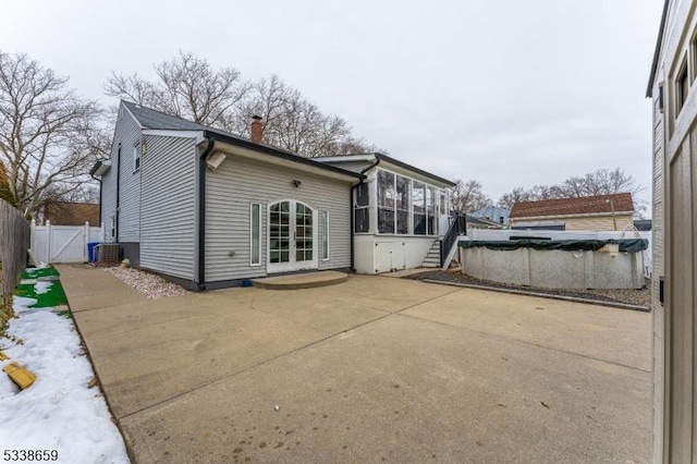 back of house with central AC unit, a sunroom, a patio, and a covered pool