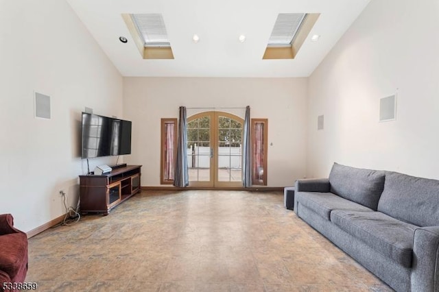 living room with french doors, a skylight, and high vaulted ceiling