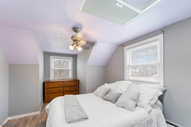 bedroom with lofted ceiling, a baseboard heating unit, ceiling fan, and light wood-type flooring