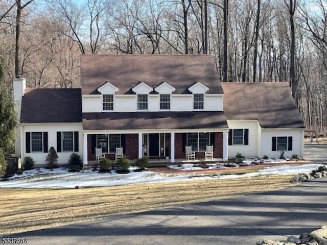 cape cod house with covered porch and a chimney