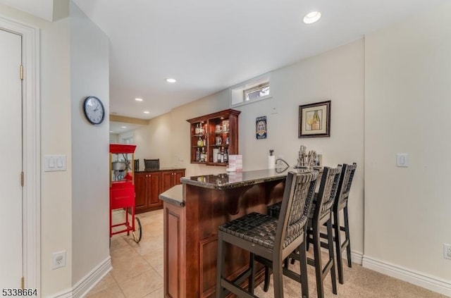 bar with recessed lighting, baseboards, a bar, and light tile patterned floors