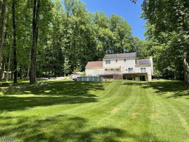 rear view of house featuring a wooden deck, a chimney, and a yard