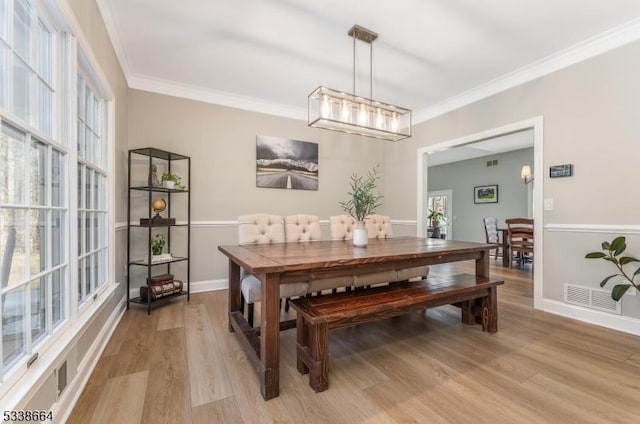 dining space featuring visible vents, crown molding, and light wood-style flooring