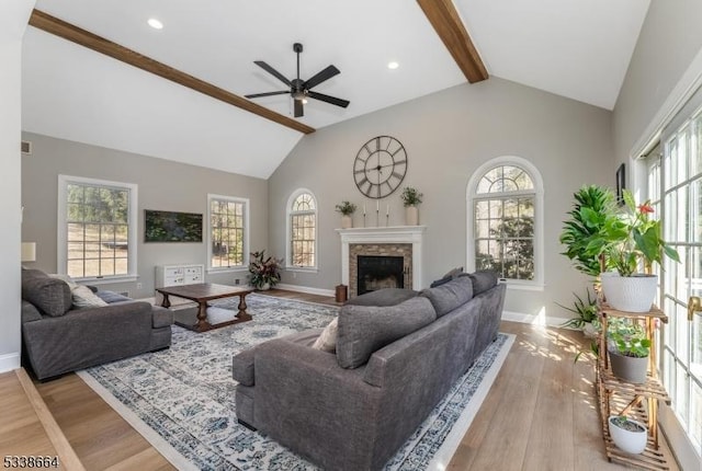 living room featuring a fireplace, beamed ceiling, a wealth of natural light, and wood finished floors