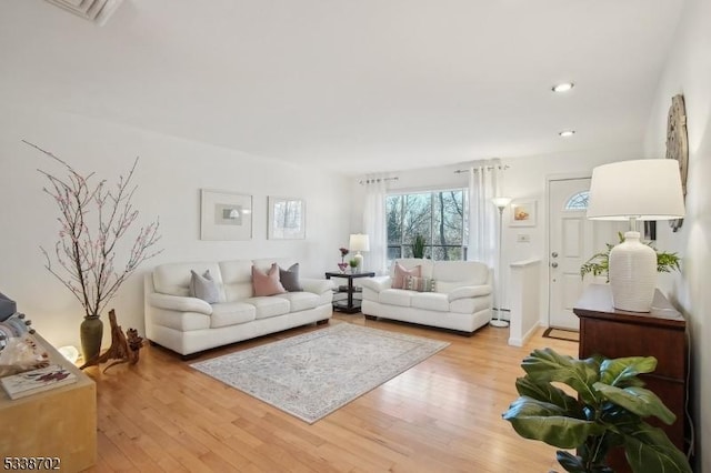 living area featuring light wood-style flooring, visible vents, a baseboard heating unit, and recessed lighting