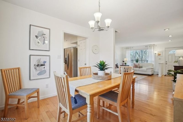 dining space with a notable chandelier, light wood-style flooring, and baseboards