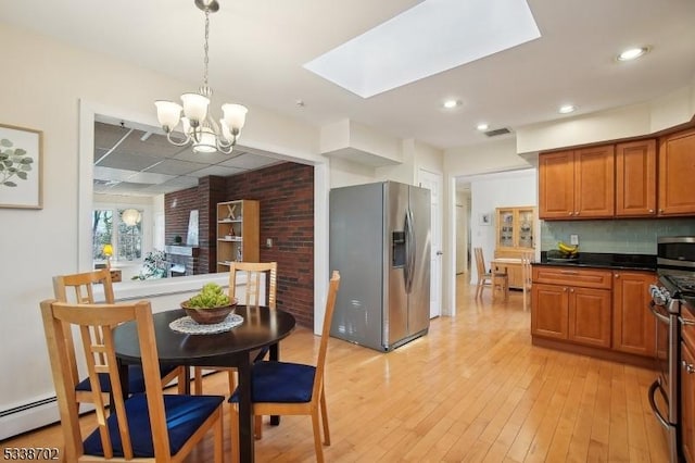 kitchen featuring appliances with stainless steel finishes, a skylight, light wood-style flooring, and brown cabinets