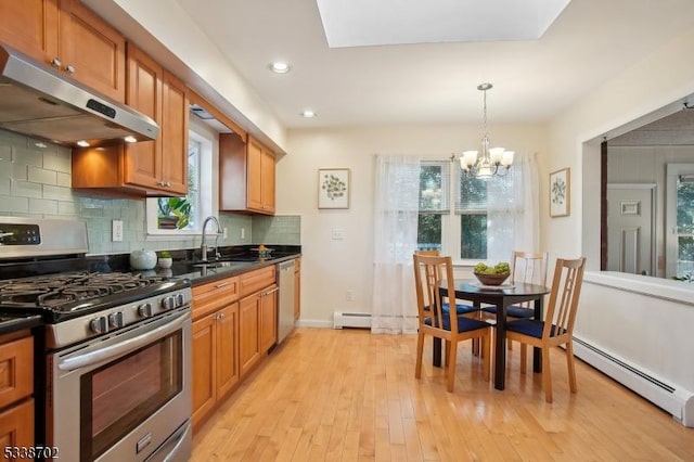 kitchen featuring dark countertops, baseboard heating, appliances with stainless steel finishes, a baseboard heating unit, and under cabinet range hood