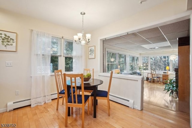 dining area with a baseboard radiator, plenty of natural light, and light wood-style flooring