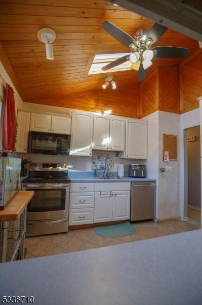 kitchen featuring light tile patterned floors, white cabinets, appliances with stainless steel finishes, and a sink