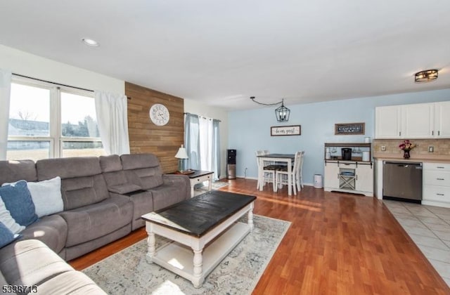 living room with light hardwood / wood-style floors and wooden walls