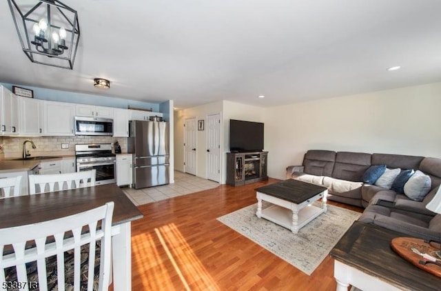 living room featuring light hardwood / wood-style flooring, sink, and a chandelier