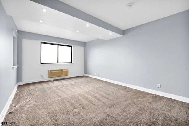 unfurnished room with beam ceiling, light colored carpet, and a wall unit AC