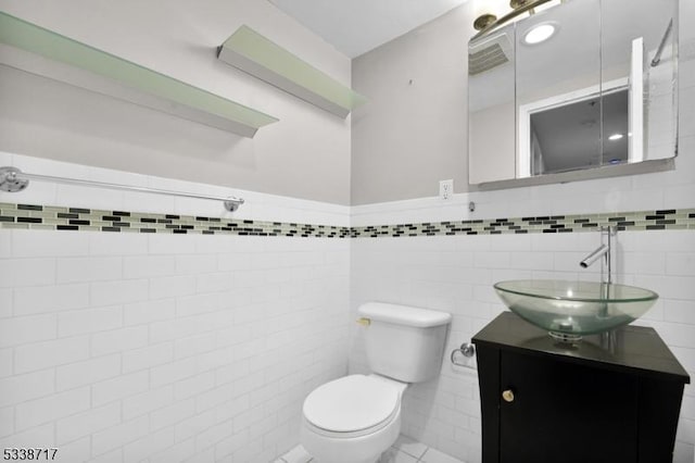 bathroom with vanity, tile walls, and toilet