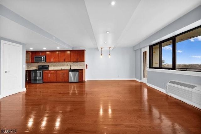 unfurnished living room featuring sink, dark wood-type flooring, and a wall unit AC