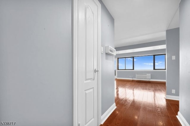 hallway with a wall mounted air conditioner and hardwood / wood-style flooring